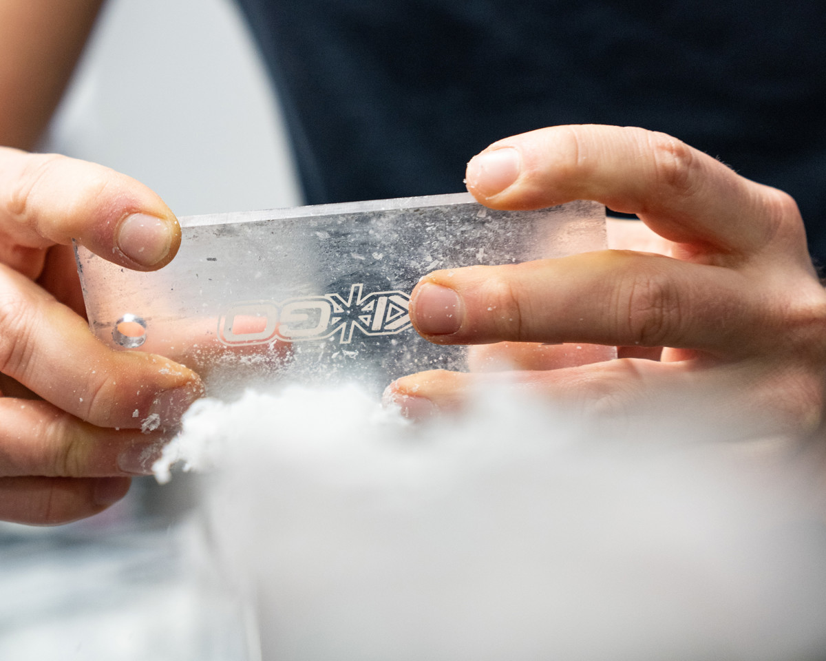 Närbild på händer som skrapar valla från ett par längdskidor.